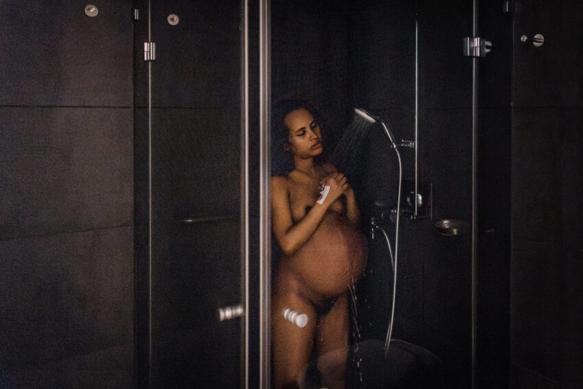 eine schwangere Frau steht unter der Dusche