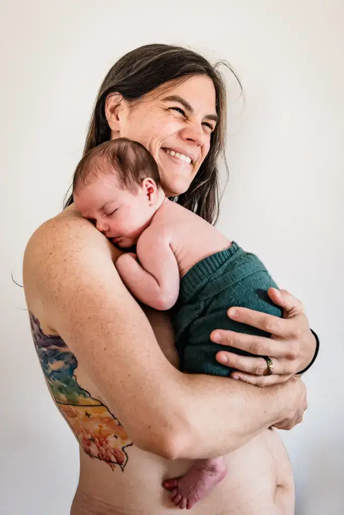 die Mama hält ihre schlafendes Neugeborenes im Arm und und ist glücklich - Neugeborenenfotografie in Dortmund und Umgebung