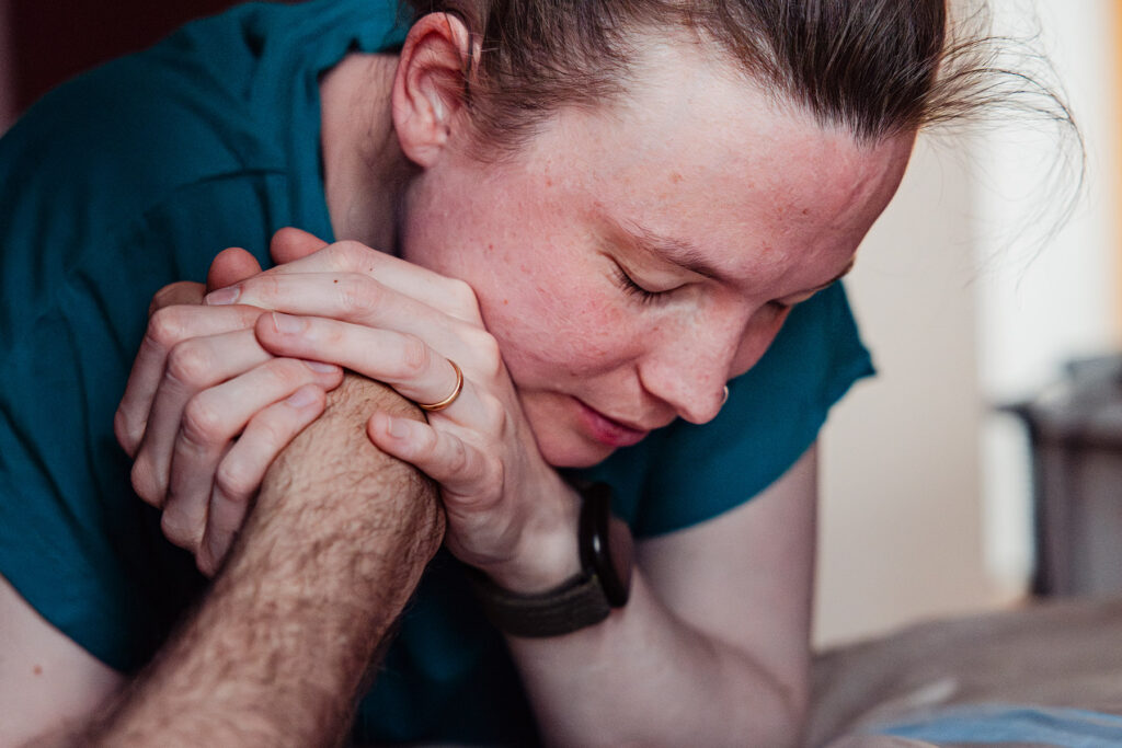 Gebärende hält die Hand ihres Partners während der Geburt – Geburtsfotografie im Geburtshaus Unna