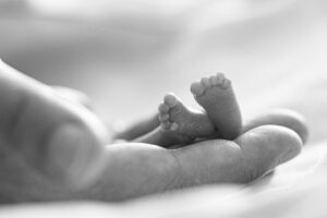 Die winzigen Füße eines Babys ruhen behutsam in den Händen eines Erwachsenen.