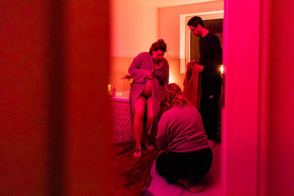 Hebamme unterstützt Gebärende beim Aussteigen aus der Badewanne während einer Hausgeburt in Dortmund